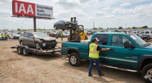 IAA Auction vehicle transport service Texas – La Chingona Trucking hotshot driver with GMC 2500HD picking up salvage car from forklift
